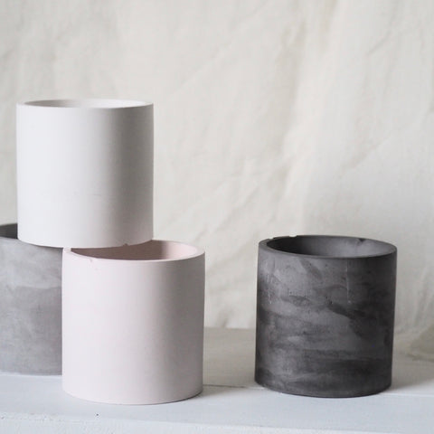 Makana concrete candle vessels, less-than-perfect, in pink, grey, white and black colors with muted white background